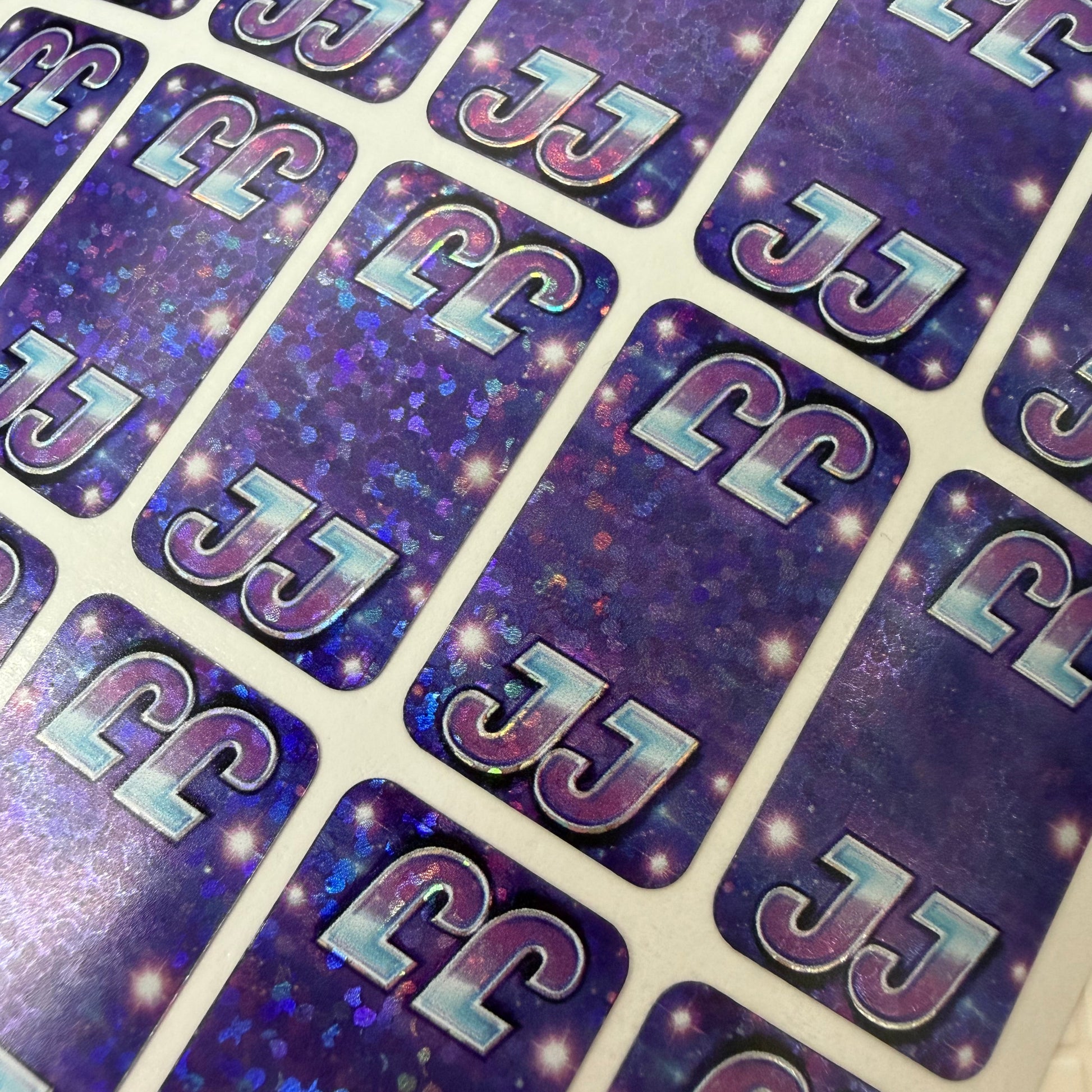 Sticker sheet with 'JJ' letters on a purple and blue gradient background
